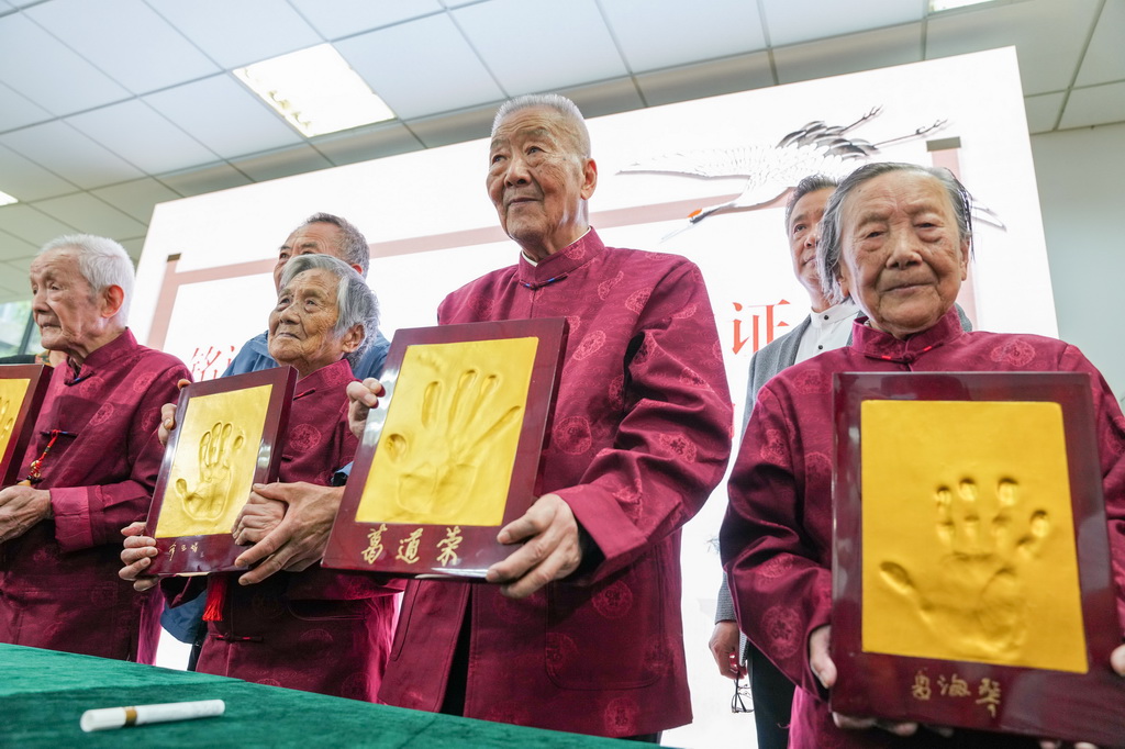 2022年10月4日,南京大屠杀幸存者夏淑琴、葛道荣、薛玉娟和王义隆(前排,从右到左)在侵华日军南京大屠杀遇难同胞纪念馆举办的重阳节活动上展示手印。新华社记者 李博 摄